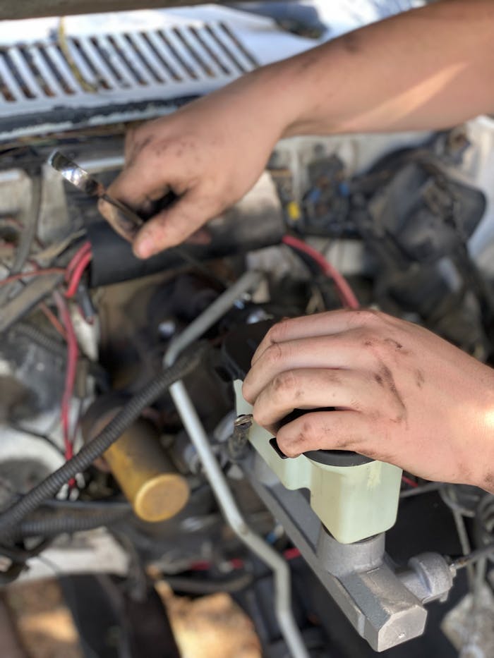 Close-up of a mechanic's hands repairing a car engine with tools and expertise.